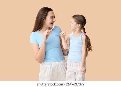 Little girl with her mother brushing teeth on beige background - Powered by Shutterstock