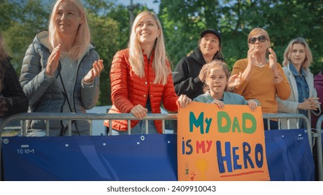 Little Girl and Her Mother Cheering for The Dad in the Audience of a City Marathon. Cute Family Holding a Motivating Banner to Support Their Loved One in a Race for Charity