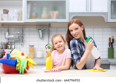 Little Girl And Her Mother Cleaning Counter In Kitchen At Home