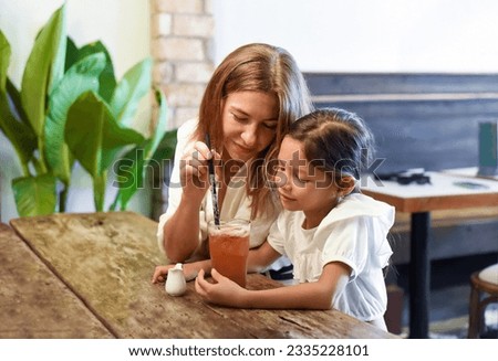 Little girl and her mother drinking ice tea together in a cafe