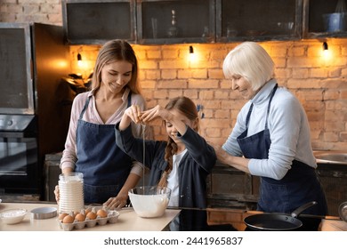 Little girl with her mother and grandmother having fun while cooking in kitchen. Happy three generation of women preparing dough for pancake, cookies, pizza , pasta - Powered by Shutterstock