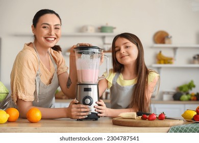 Little girl and her mother making smoothie with blender in kitchen - Powered by Shutterstock