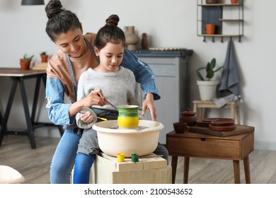 Little girl with her mother painting ceramic pot at home - Powered by Shutterstock