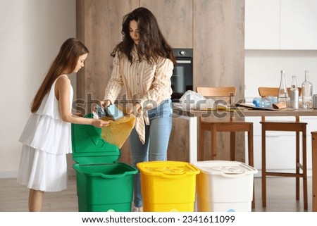 Little girl with her mother sorting paper garbage in kitchen