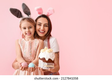 Little girl, her mother with tasty Easter cake and eggs on pink background