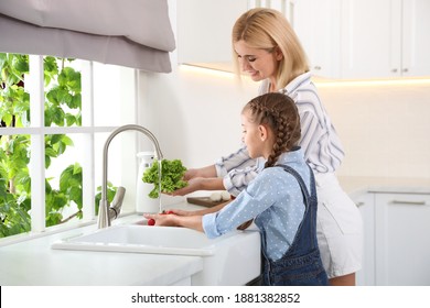 Little girl with her mother washing vegetables together in modern kitchen - Powered by Shutterstock