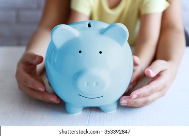Little girl with her mum and pig  moneybox closeup