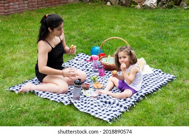 Little Girl And Her Sister Are Playing Games And Having A Picnic In The Garden