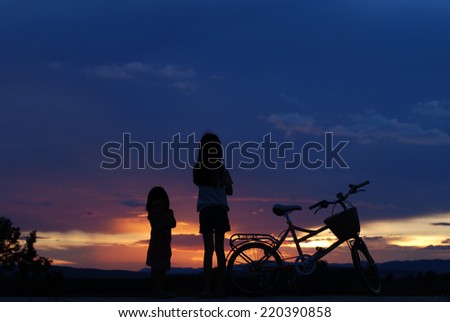 little girl with her sister watching the  beautiful sunset.Silhouette,