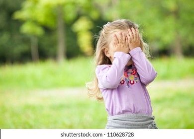 Little girl hiding face outdoor portrait