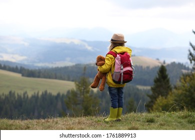 Little girl with hiking backpack and teddy bear in the mountains. Solitude in the mountains. Hiking, backpacking,walking with child. 