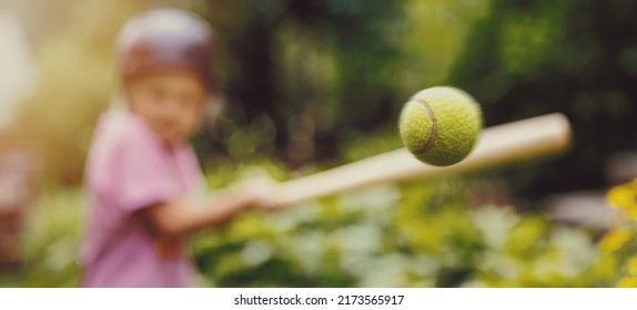 little girl hitting tennis ball with baseball bat at park. batting practice. copy space