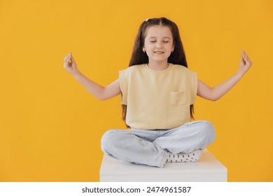 A little girl hold hands in yoga om aum gesture relax meditate try calm, isolated on yellow background - Powered by Shutterstock