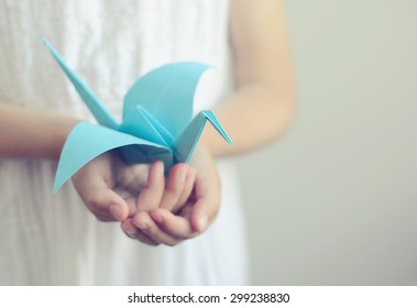 Little Girl Holding A Blue Origami Bird In Her Hands