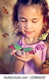 Little girl holding a butterfly in a field