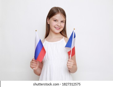 Little girl holding flags of Russian Federation and France.