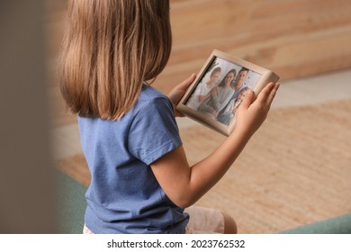 Little Girl Holding Framed Family Photo Indoors, Closeup