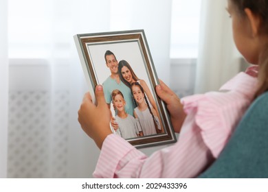 Little Girl Holding Framed Family Photo Indoors, Closeup