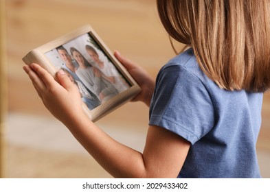 Little Girl Holding Framed Family Photo Indoors, Closeup