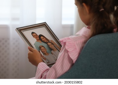 Little Girl Holding Framed Family Photo Indoors, Closeup