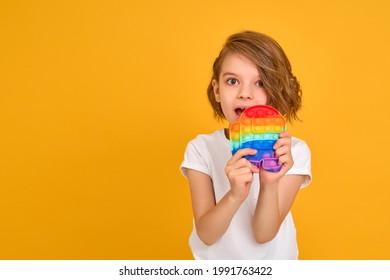 little girl holding pop it antistress toy on yellow background, isolate. copyspace  - Shutterstock ID 1991763422