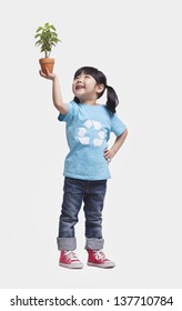 Little Girl Holding Potted Plant Above Her Head, Studio Shot