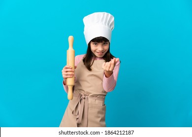 Little Girl Holding A Rolling Pin Isolated On Blue Background Making Money Gesture