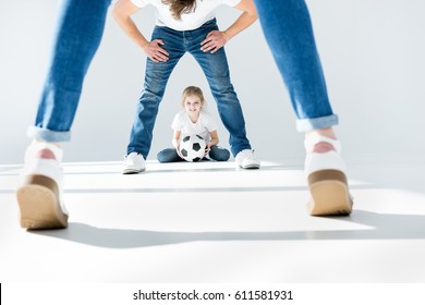 Little Girl Holding Soccer Ball With Parents In Front On White