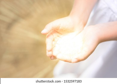 Little girl holding the sun in her hands. bright light comes from the hands of child. concept miracle, magic, share, give, offer, care