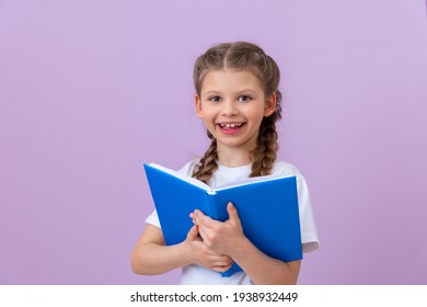 A little girl holds a book and is happy.