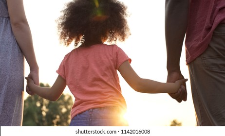 Little girl holds fathers and mothers hands, happiness and wellbeing in family