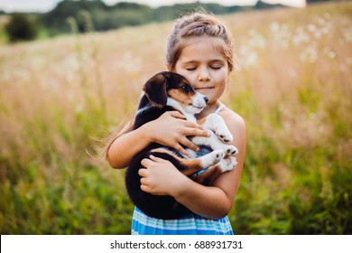 Kleines Mädchen hält einen Welpen auf den Armen