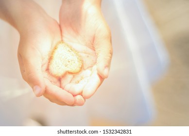 Little Girl Holds A Shining Heart In Her Hands. Light In The Hands Of Child. Concepts Of Miracle, Magic, Sharing, Giving, Offering, Caring, Protecting Love And Peace