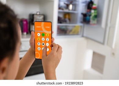 little girl holds a smartphone and controls the refrigerator, smart home