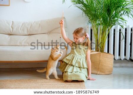 little girl at home in the bedroom playing with a cat