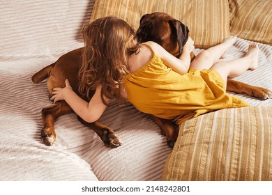 Little Girl At Home On The Couch Playing With Her Big Dog