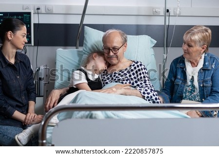 Little girl hugging grandfather at sanatorium room before surgery in medical tower. Hospitalized old man saying goodbye to close family members at elderly people hospital.