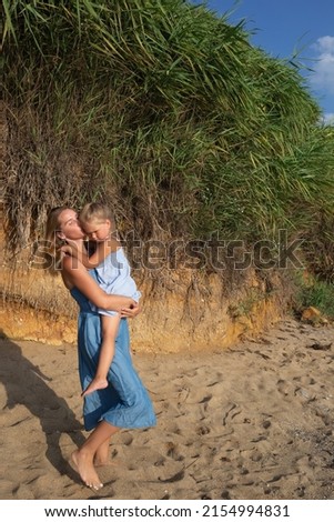 little girl hugging her mom at sunset on the beach near the sea. family portrait