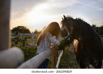 Little girl hugging horse outdoors at community farm. - Powered by Shutterstock