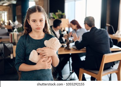 Little Girl Is Hugging Teddy Bear At Office Of Family Lawyer. Registration Of Guardianship. Family In Office Of Family Lawyer.