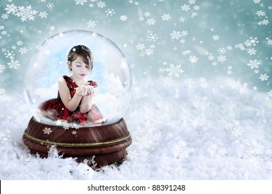 Little girl inside a Christmas snow globe blowing snow out of her hands. Copy space available. Shallow depth of field with selective focus on snowglobe. - Powered by Shutterstock