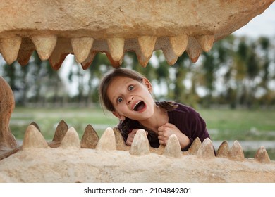 Little Girl Inside Of  Dinosaur's Mouth In Dino Park. Children In Dinosaur Park.