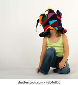 Little Girl In Jeans And Shirt In A Funny Hat Too Big For Her Covering Her Face