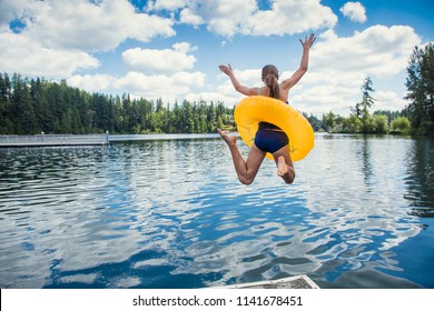 A little girl jumping off the dock into a beautiful mountain lake. Having fun on a summer vacation