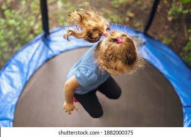 Little girl jumping on a trampoline on a summer day.