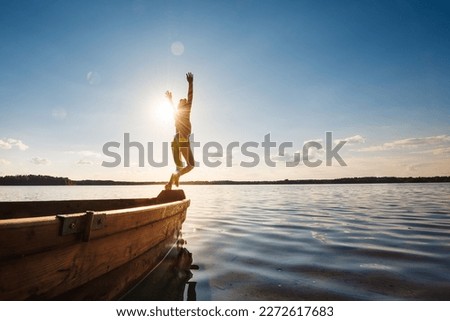 Little girl jumps into water from a wooden boat.