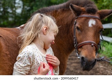 Little Girl Laugh With Pony Horse In Equestrian Club