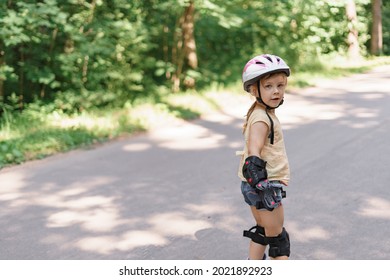 Little Girl Learning To Roller Skate. Baby In Protective Sportswear