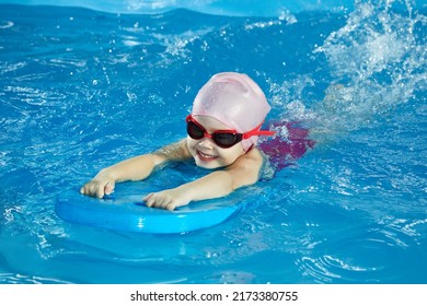 Little girl learning to swim in indoor pool with pool board - Shutterstock ID 2173380755