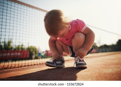 little girl learning to tie shoelaces - Powered by Shutterstock